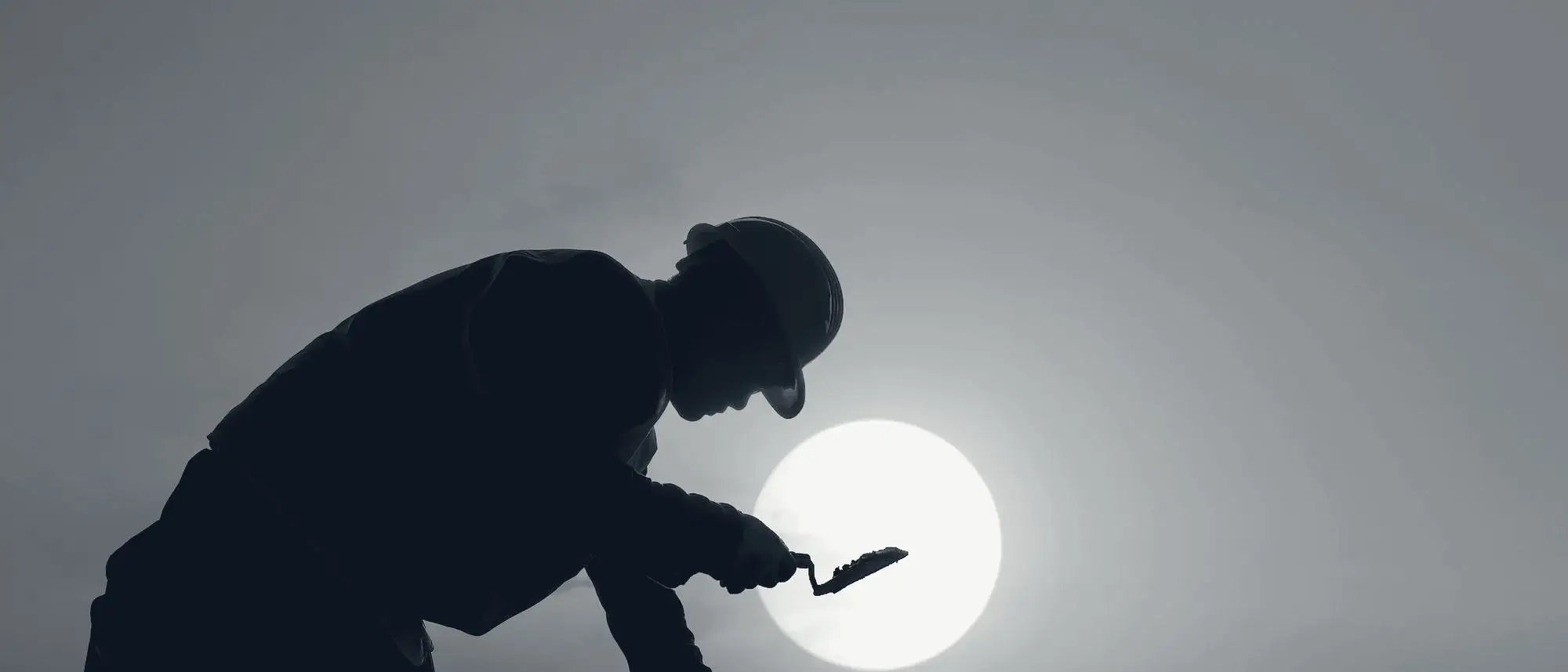 Worker silhouetted against the setting sun on a job site