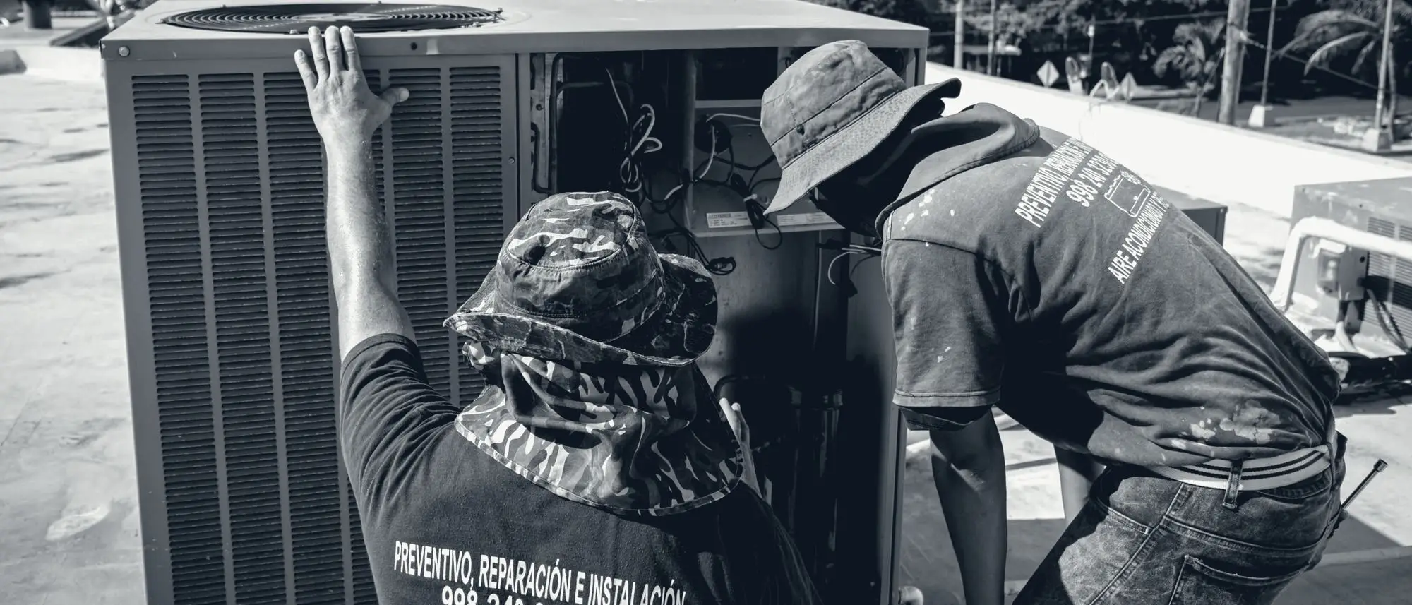 Two HVAC technicians working on rooftop condenser units