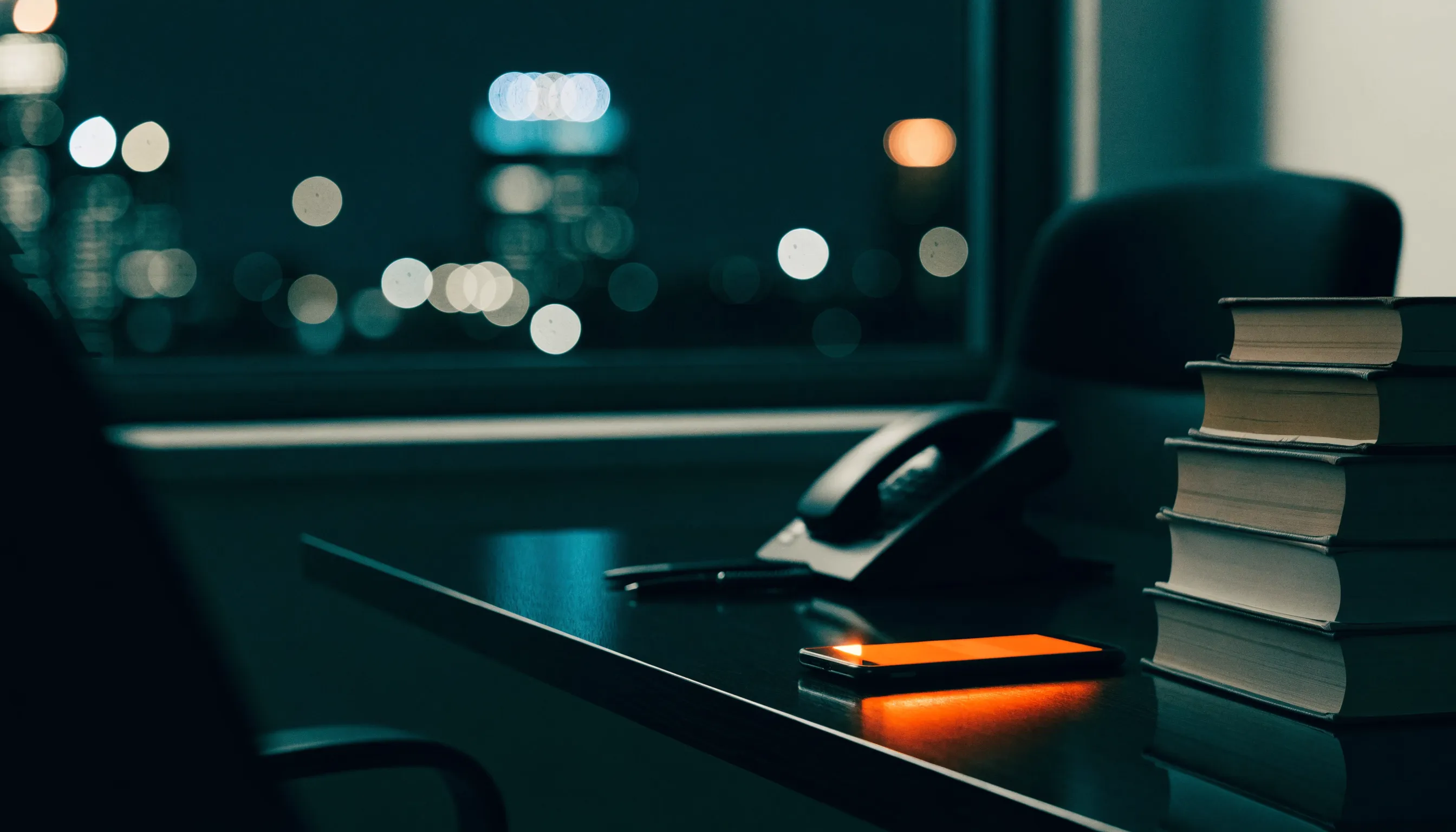 A dark law office at night with a phone glowing orange on the desk