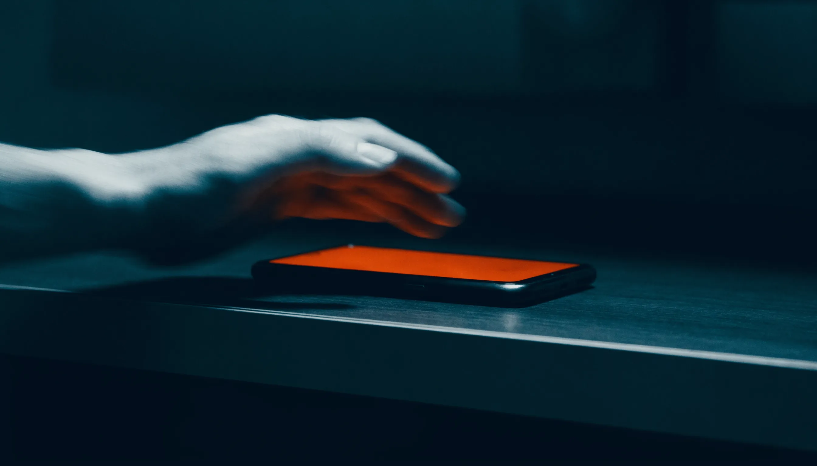 A motion-blurred hand reaching fast for a ringing phone glowing orange