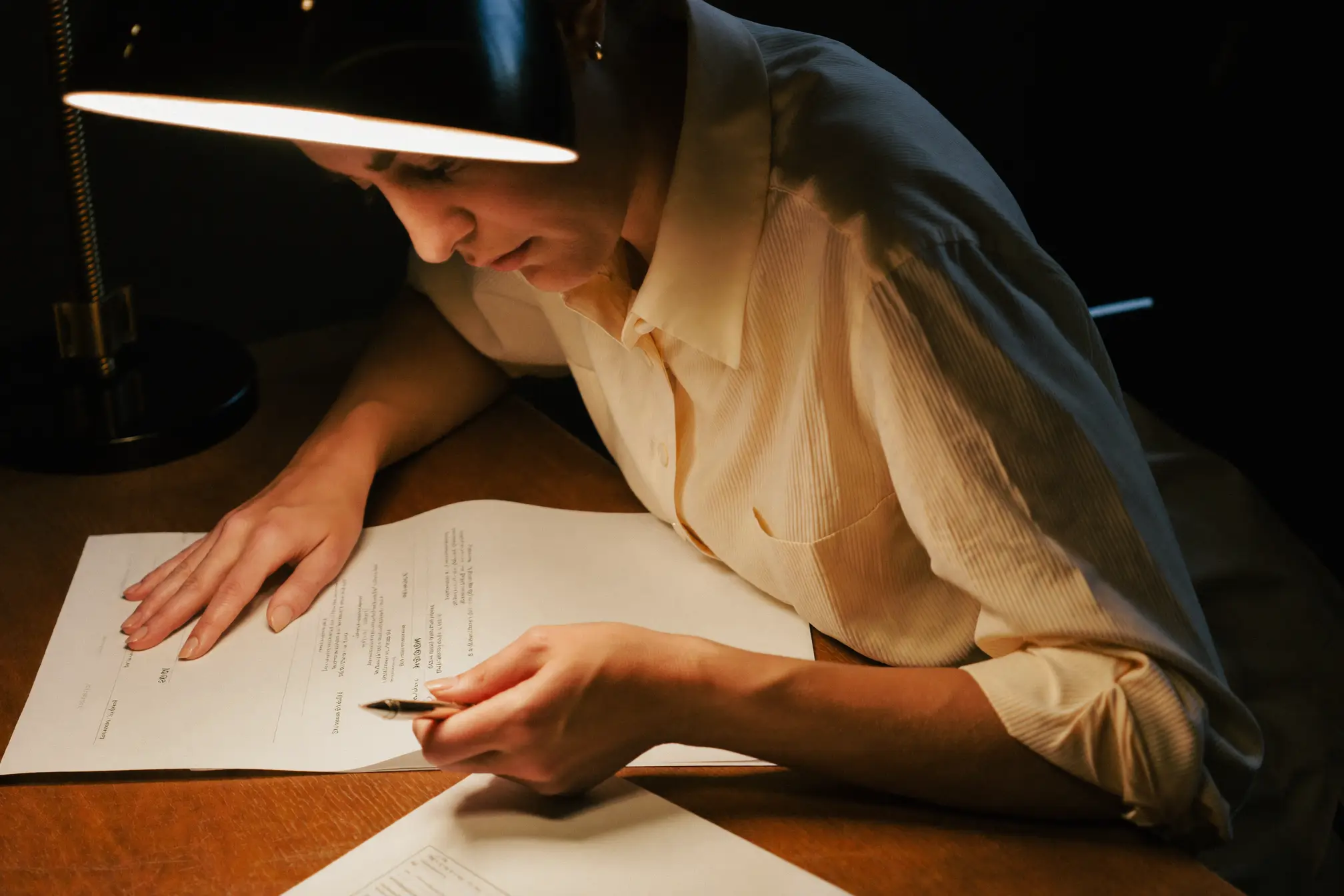 An accountant reviewing printed statements under a desk lamp