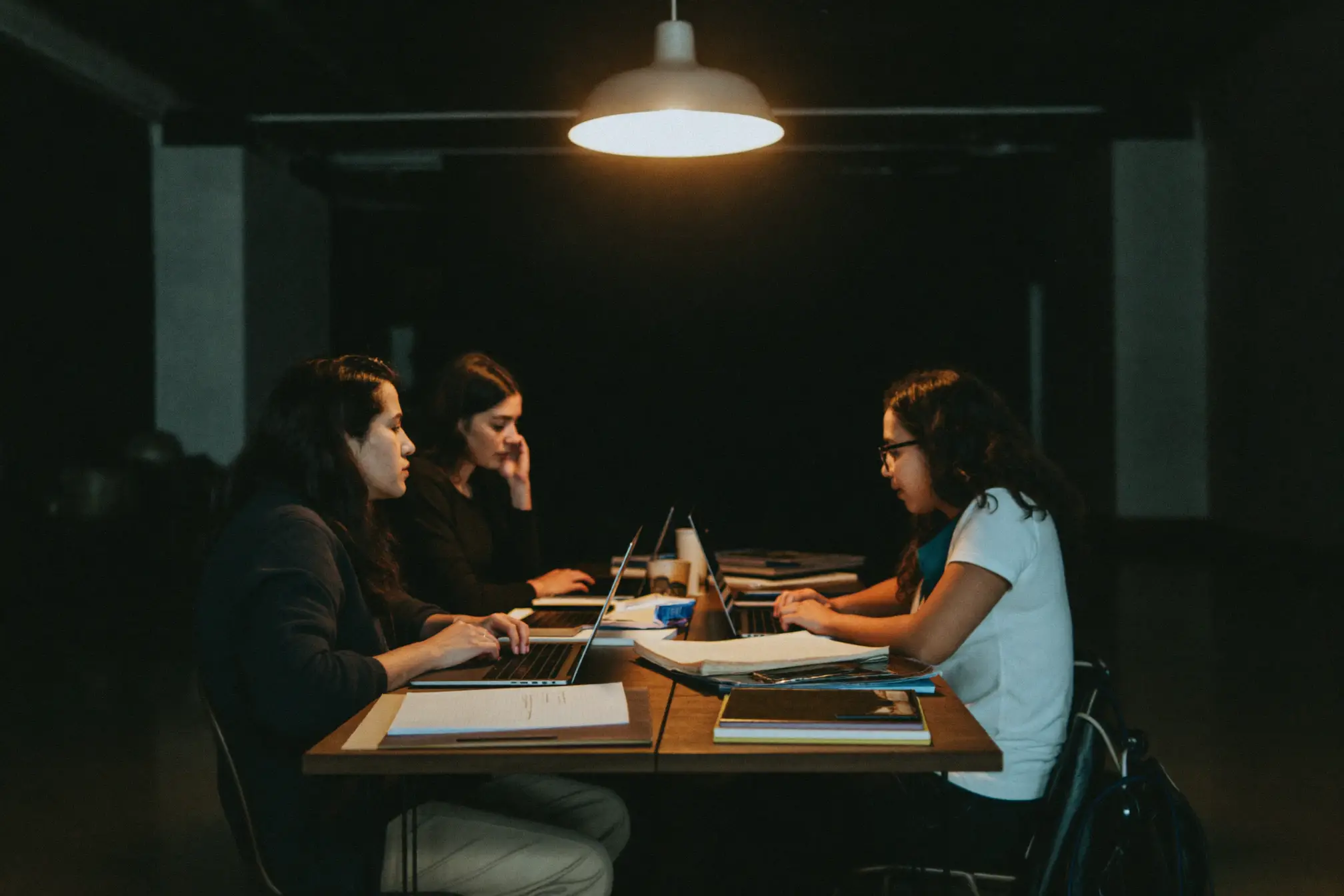 A small agency team working at a long table under a pendant light