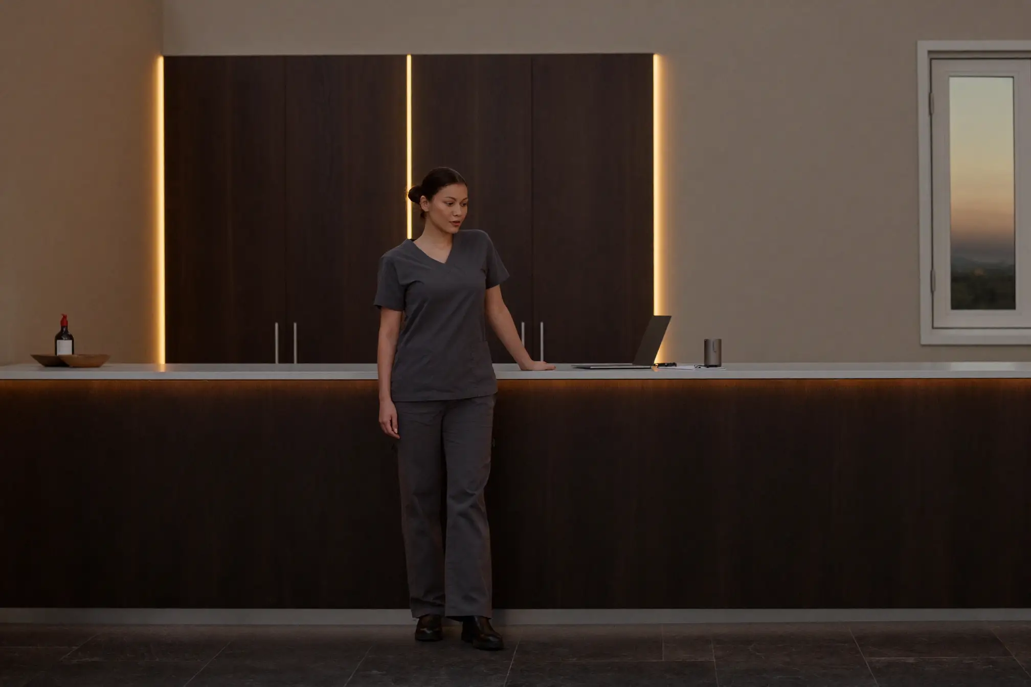 A clinician at the reception counter of a minimalist clinic at dusk